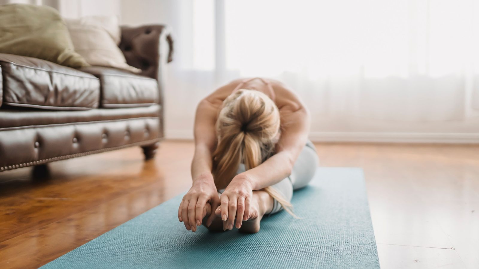 Une femme fait des étirements sur un tapis dans son salon